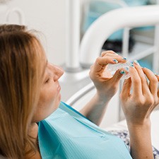 Patient in treatment chair holding clear aligner