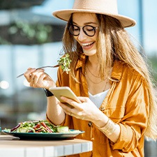 Woman checking her phone while eating lunch